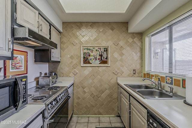 kitchen with black appliances, light countertops, under cabinet range hood, and a sink