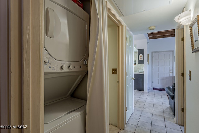 washroom with stacked washing maching and dryer, laundry area, and light tile patterned flooring