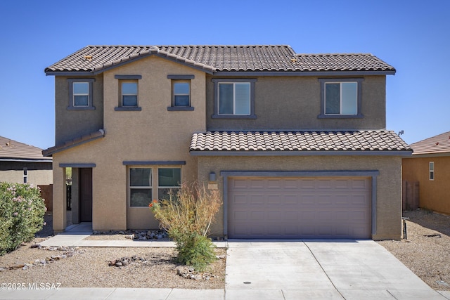 mediterranean / spanish house featuring a tiled roof, an attached garage, concrete driveway, and stucco siding