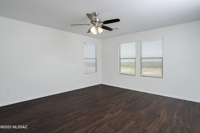 empty room featuring baseboards, a ceiling fan, dark wood-style floors, and visible vents