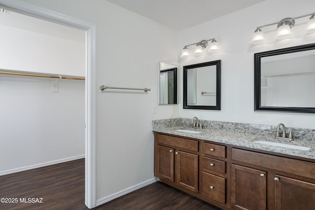 full bath featuring double vanity, baseboards, a sink, and wood finished floors