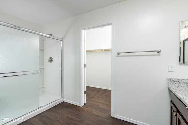 full bathroom featuring vanity, baseboards, wood finished floors, and a shower stall