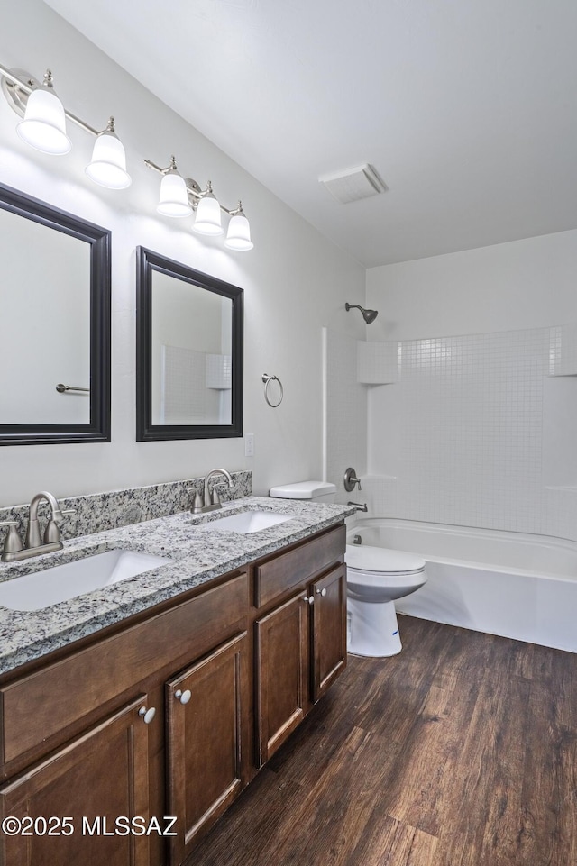bathroom with a sink, toilet, wood finished floors, and shower / washtub combination