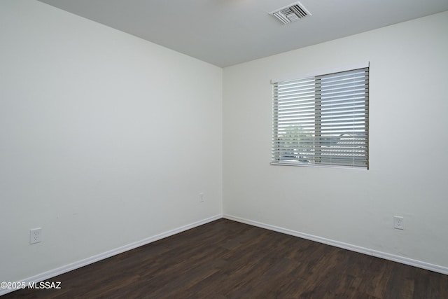 spare room featuring baseboards, dark wood-style floors, and visible vents