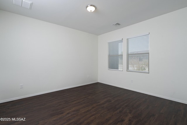 unfurnished room with dark wood-style flooring, baseboards, and visible vents