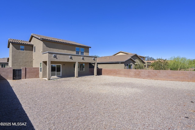 rear view of property featuring a tiled roof, central AC, a fenced backyard, a patio, and stucco siding