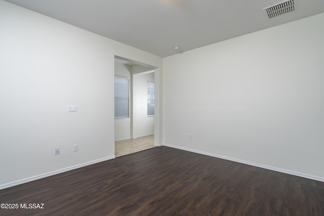 spare room featuring baseboards, wood finished floors, and visible vents