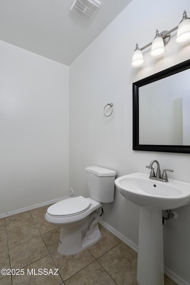 half bath with baseboards, tile patterned floors, toilet, and visible vents