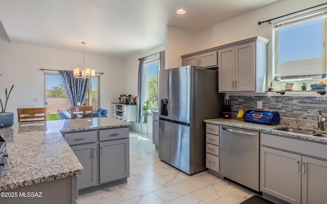 kitchen with a notable chandelier, a sink, gray cabinetry, marble finish floor, and stainless steel appliances
