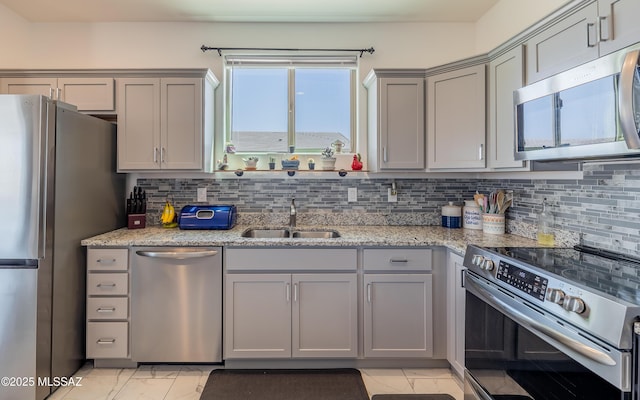 kitchen featuring appliances with stainless steel finishes, a sink, gray cabinets, marble finish floor, and decorative backsplash