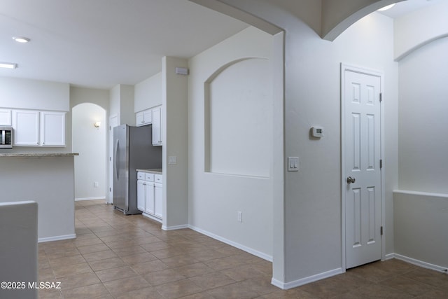 493 E Placita Nodo, Sahuarita, AZ 85629 - kitchen with tile patterned flooring, arched walkways, white cabinetry, and appliances with stainless steel finishes
