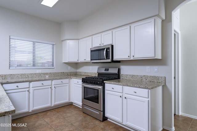 493 E Placita Nodo, Sahuarita, AZ 85629 - kitchen featuring light stone countertops, tile patterned flooring, arched walkways, stainless steel appliances, and white cabinetry