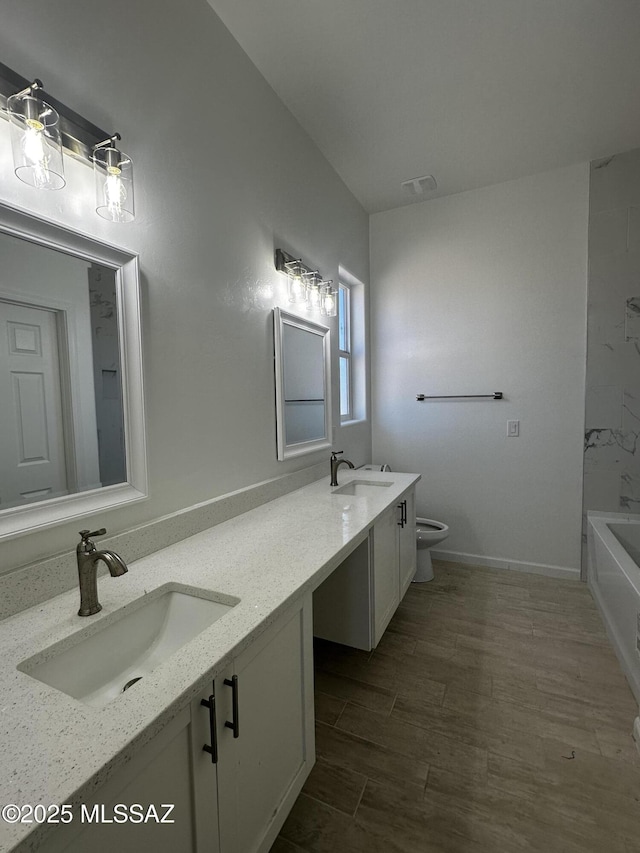 full bath featuring a sink, toilet, double vanity, and wood finished floors