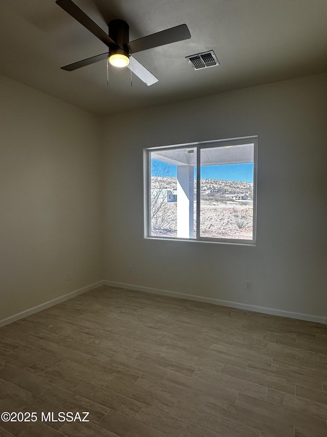 empty room featuring visible vents, baseboards, ceiling fan, and wood finished floors