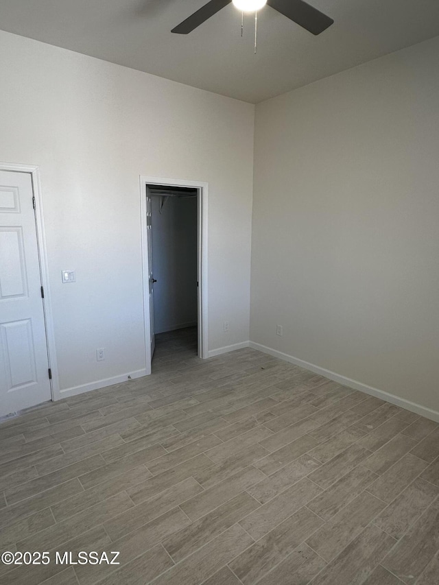 empty room with baseboards, a ceiling fan, and wood finished floors