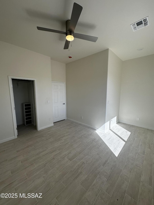 unfurnished bedroom with visible vents, baseboards, ceiling fan, and wood finished floors
