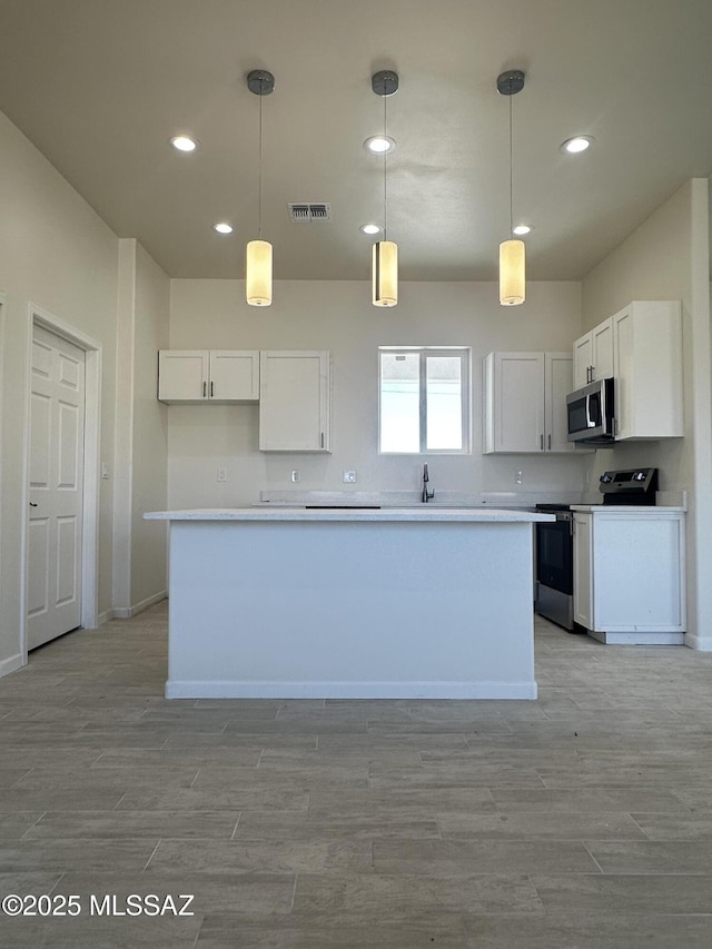 kitchen featuring recessed lighting, stainless steel microwave, range with electric cooktop, and visible vents
