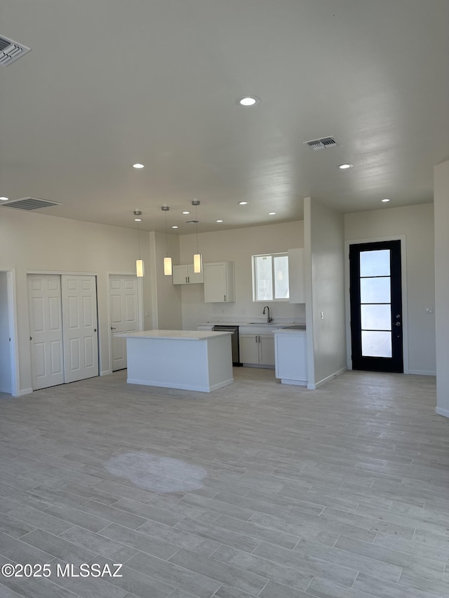 kitchen featuring white cabinetry, open floor plan, recessed lighting, baseboards, and a kitchen island