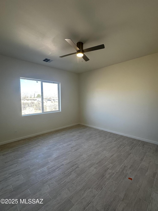 unfurnished room featuring a ceiling fan, baseboards, visible vents, and dark wood finished floors