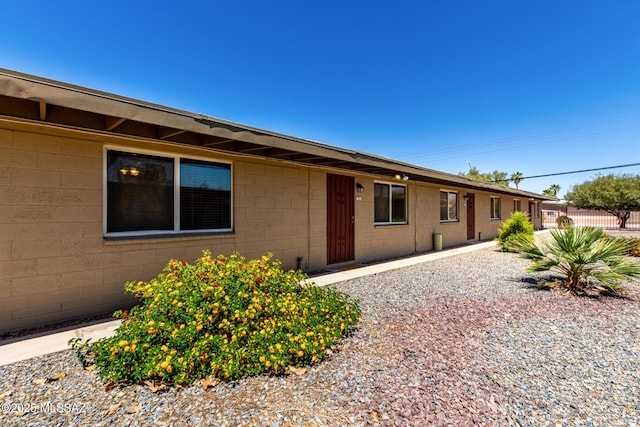 exterior space featuring concrete block siding and fence
