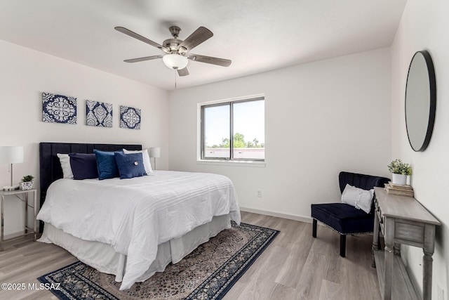 bedroom with a ceiling fan, baseboards, and light wood-style flooring