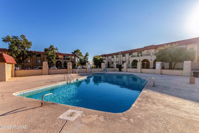 pool with a patio and fence