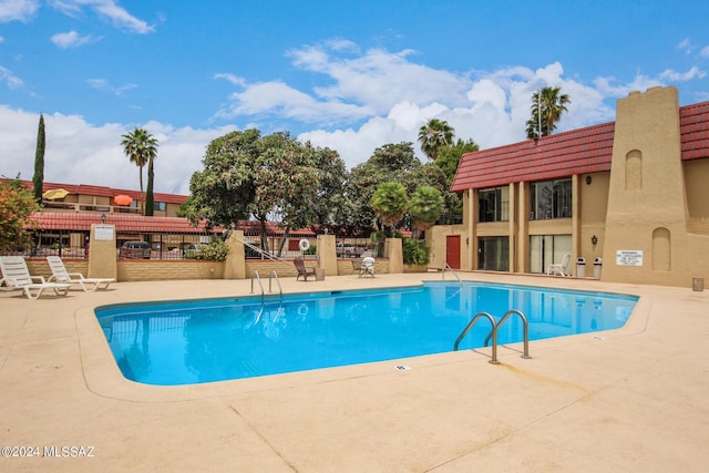 community pool with a patio area and fence