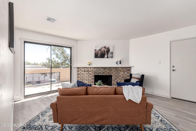 living room with a fireplace, light wood finished floors, and visible vents