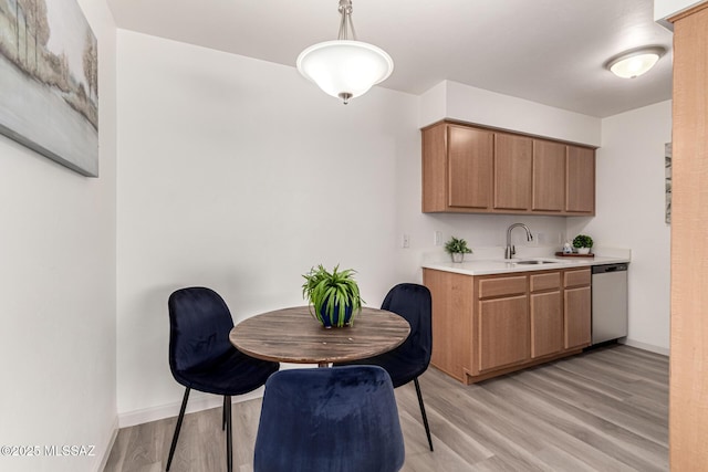 kitchen with a sink, light countertops, light wood-type flooring, and dishwasher