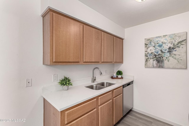 kitchen featuring stainless steel dishwasher, baseboards, light wood-type flooring, light countertops, and a sink