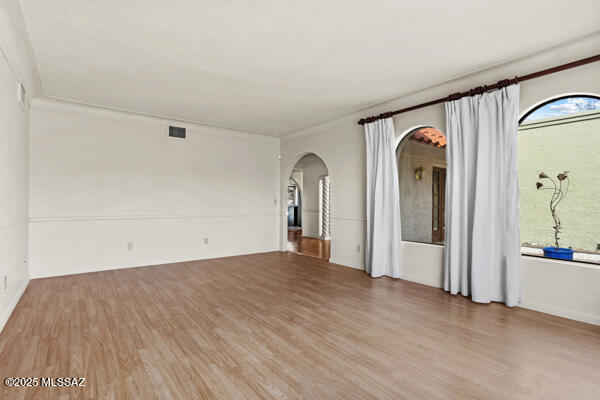4361 N Wilmot Rd, Tucson, AZ 85750 - empty room featuring arched walkways, ornamental molding, wood finished floors, and visible vents