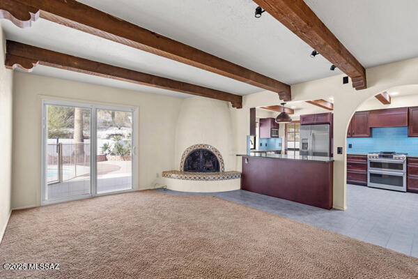 4361 N Wilmot Rd, Tucson, AZ 85750 - unfurnished living room featuring arched walkways, a large fireplace, and beam ceiling