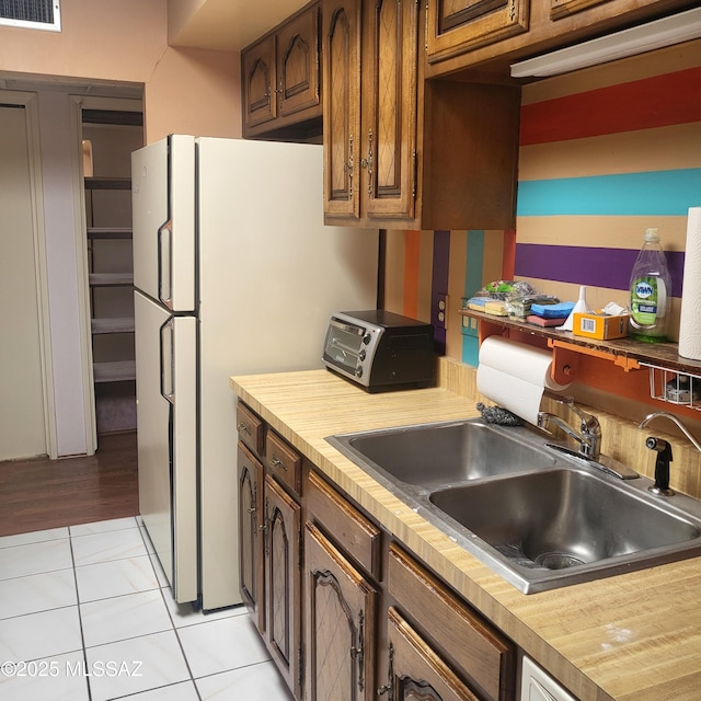 kitchen with visible vents, a toaster, light countertops, a sink, and light tile patterned floors