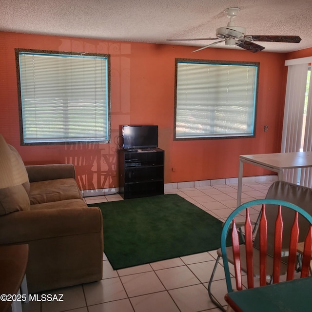 living room with tile patterned flooring, a ceiling fan, and a textured ceiling
