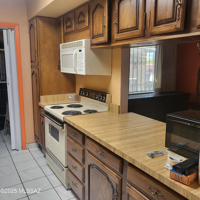 kitchen featuring white appliances, light tile patterned floors, and light countertops