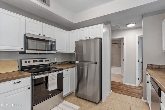 1500 E Pusch Wilderness Dr Unit 10105, Oro Valley, AZ 85737 - kitchen featuring stainless steel appliances, white cabinets, light tile patterned floors, and baseboards