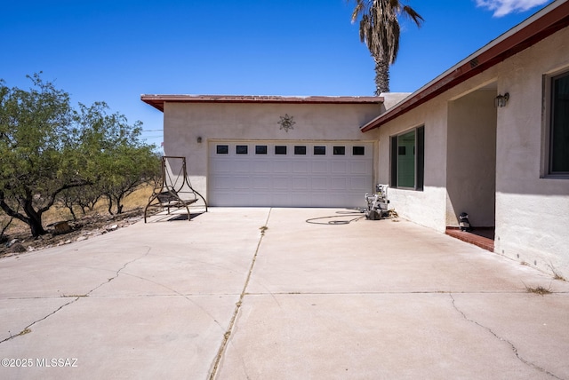 view of side of home featuring concrete driveway, an attached garage, and stucco siding