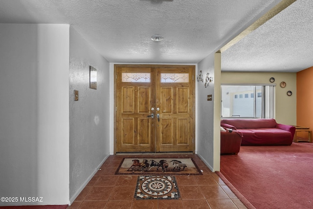tiled foyer featuring a textured ceiling, baseboards, and a textured wall