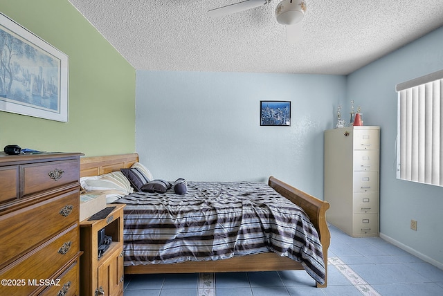 bedroom with baseboards, light tile patterned flooring, and a textured ceiling