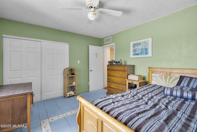 bedroom with visible vents, tile patterned flooring, a closet, a textured ceiling, and a ceiling fan