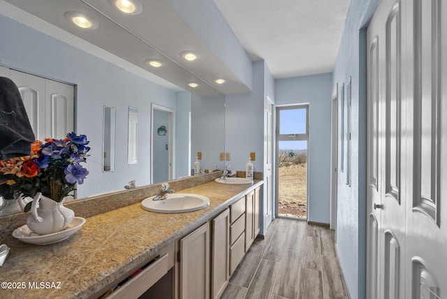 bathroom with double vanity, recessed lighting, a sink, and wood finished floors