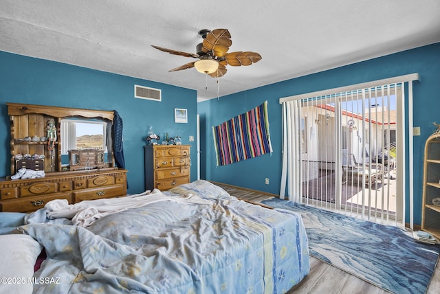 bedroom with visible vents, wood finished floors, access to exterior, a textured ceiling, and a ceiling fan