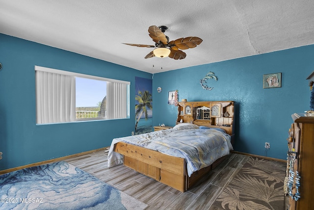 bedroom featuring baseboards, a ceiling fan, a textured ceiling, and wood finished floors