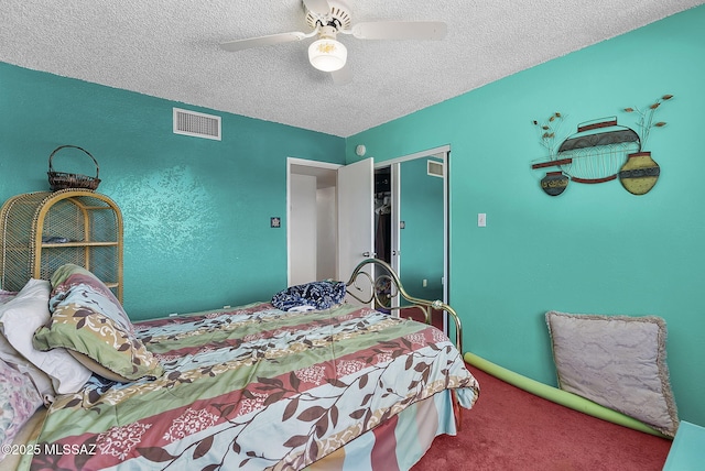 carpeted bedroom featuring visible vents, a textured ceiling, ceiling fan, and a closet