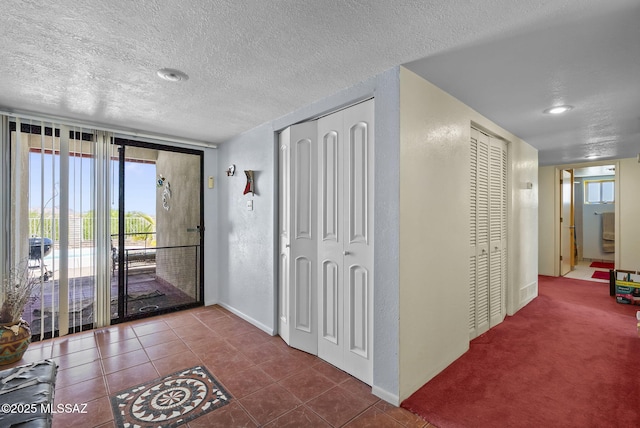 tiled entryway featuring baseboards, a textured ceiling, and a textured wall
