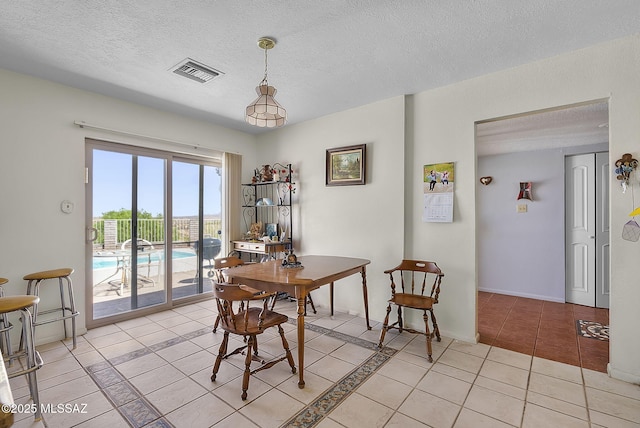 dining area with light tile patterned floors, baseboards, a textured ceiling, and visible vents
