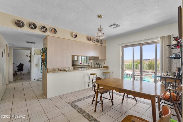 dining room featuring light tile patterned floors, a textured ceiling, and visible vents
