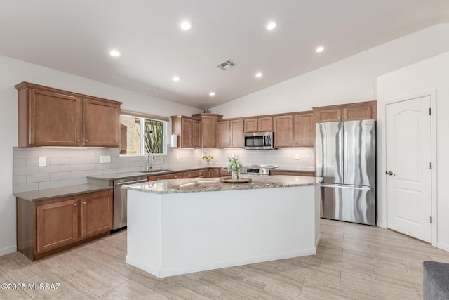 13795 N Buckhorn Cholla Dr, Marana, AZ 85658 - kitchen featuring appliances with stainless steel finishes, a sink, a kitchen island, decorative backsplash, and brown cabinetry