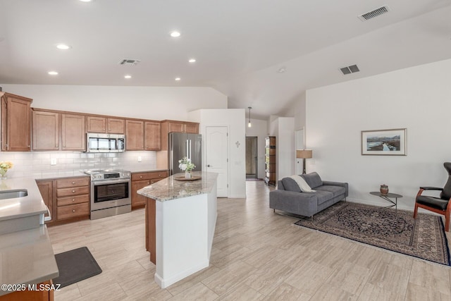 13795 N Buckhorn Cholla Dr, Marana, AZ 85658 - kitchen with appliances with stainless steel finishes, lofted ceiling, a center island, tasteful backsplash, and brown cabinets