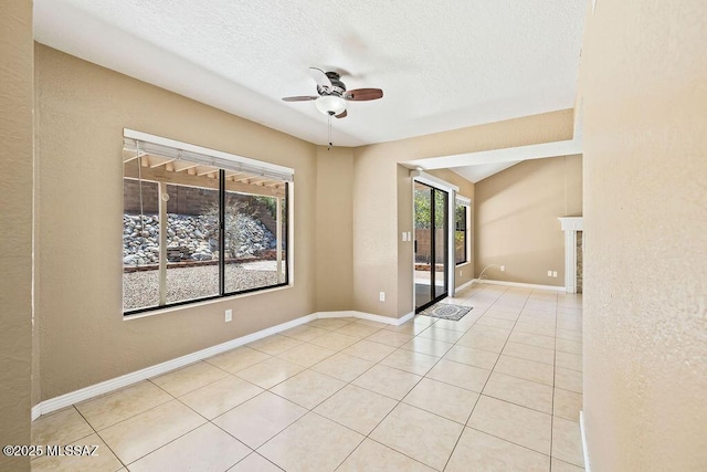 tiled empty room with a textured ceiling, baseboards, and ceiling fan